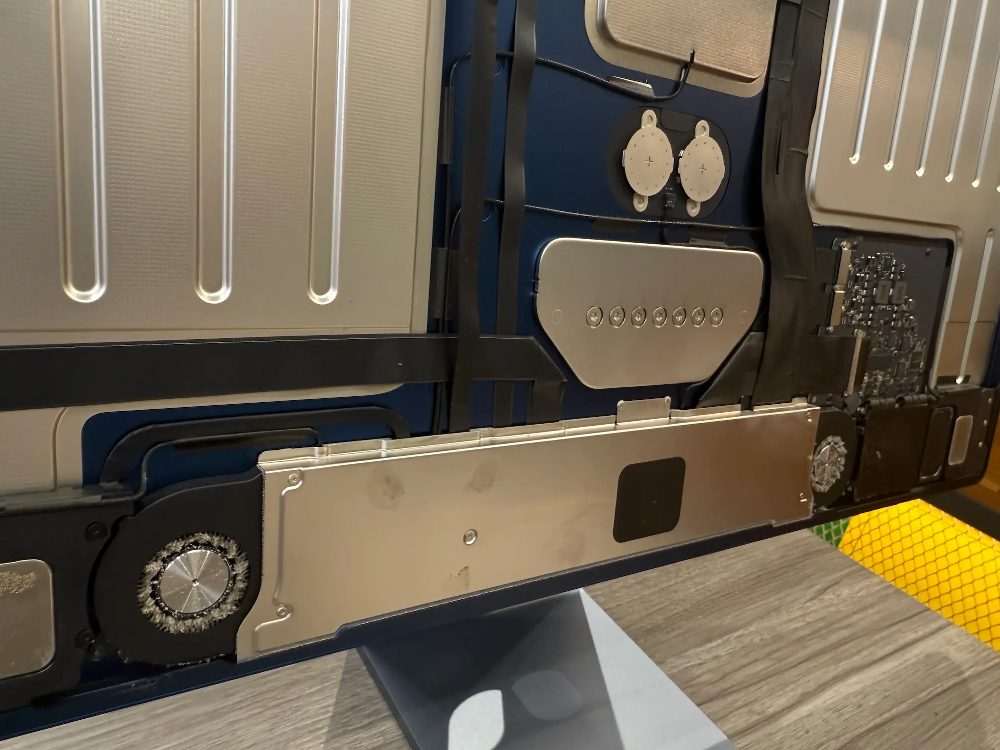 iMac 24 內部散熱構造圖：展示位於機身下方的風扇模組與進氣空間，強調保持氣流暢通對預防螢幕災情的重要性