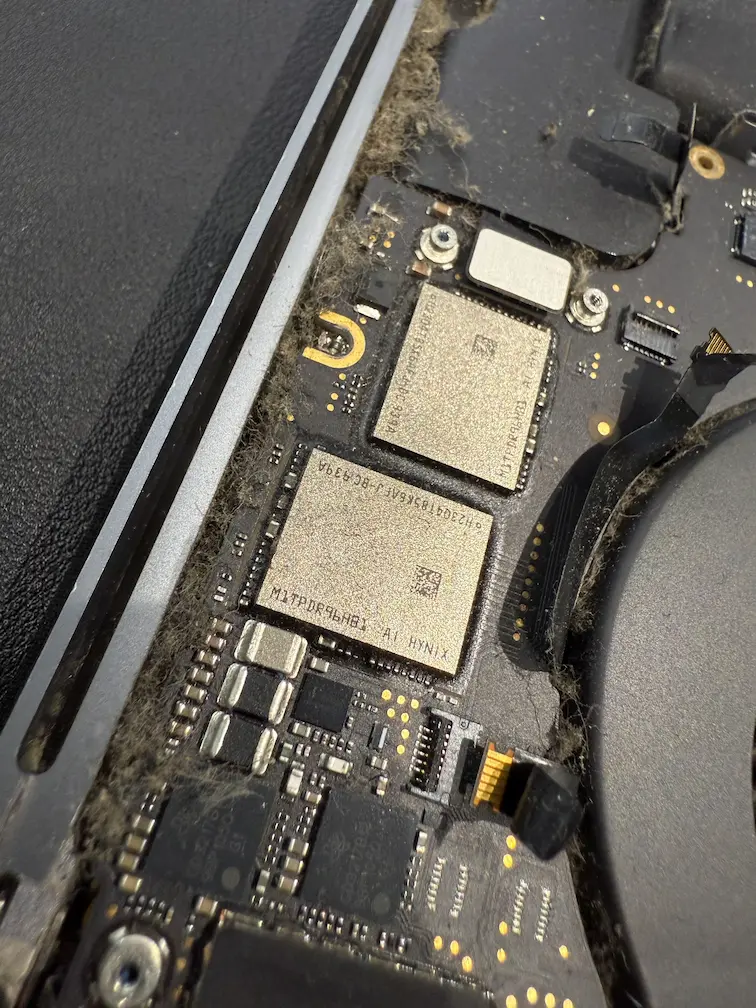 MacBook 內部清理：主機板微小元件上的積塵特寫，影響電子零件散熱