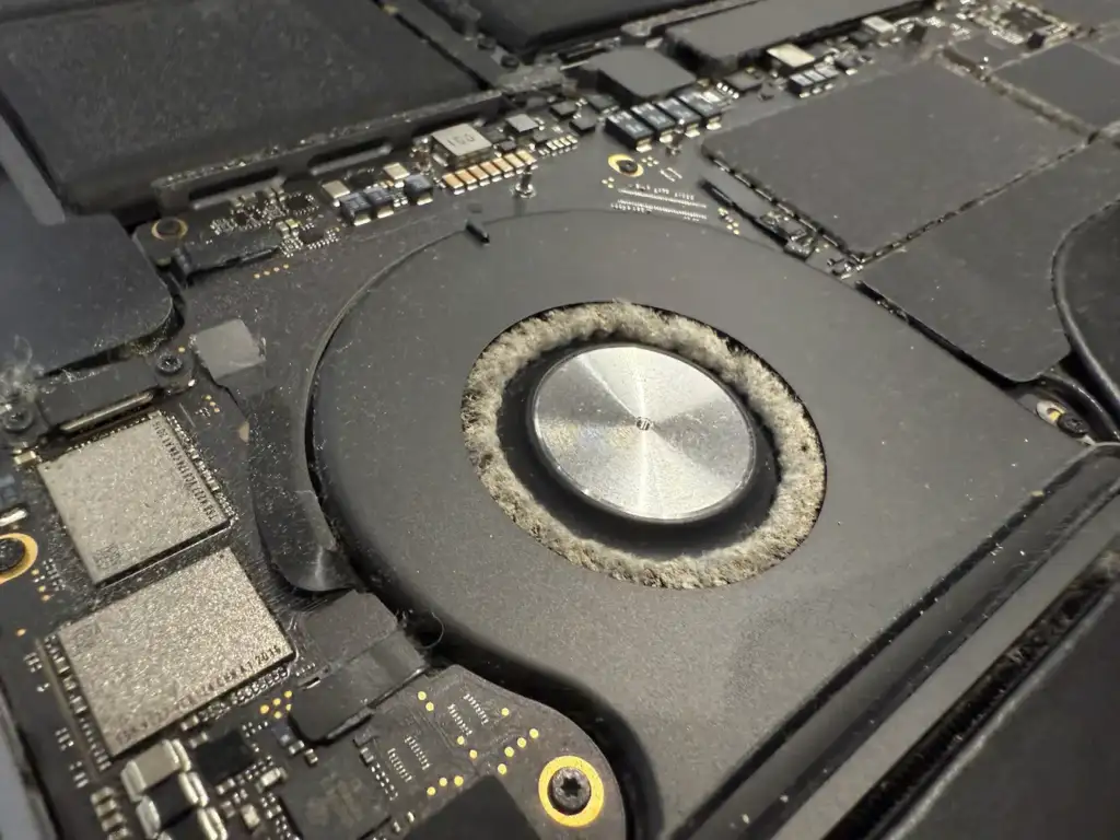 MacBook 風扇進氣口積塵：風扇邊緣佈滿厚重棉絮阻礙氣流，專業 MacBook 散熱保養可有效改善發燙問題
