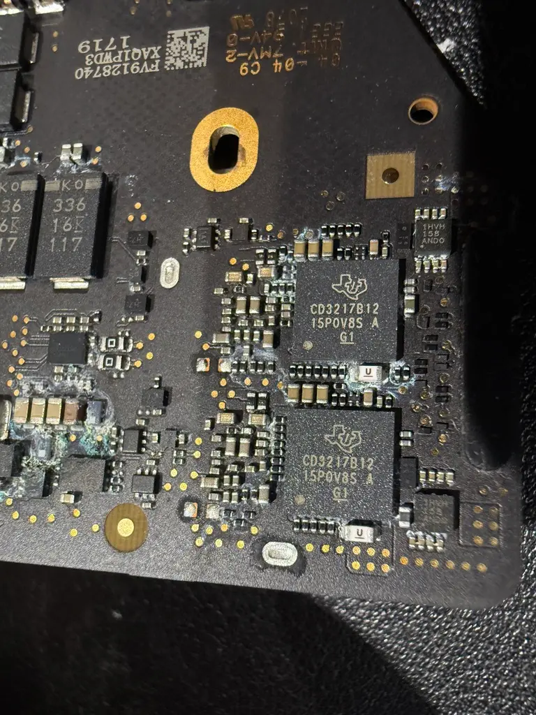 MacBook 主機板 USB-C 供電控制晶片 CD3217 微距特寫,周圍可見明顯的液體腐蝕痕跡,為導致無法充電與不開機的常見故障點