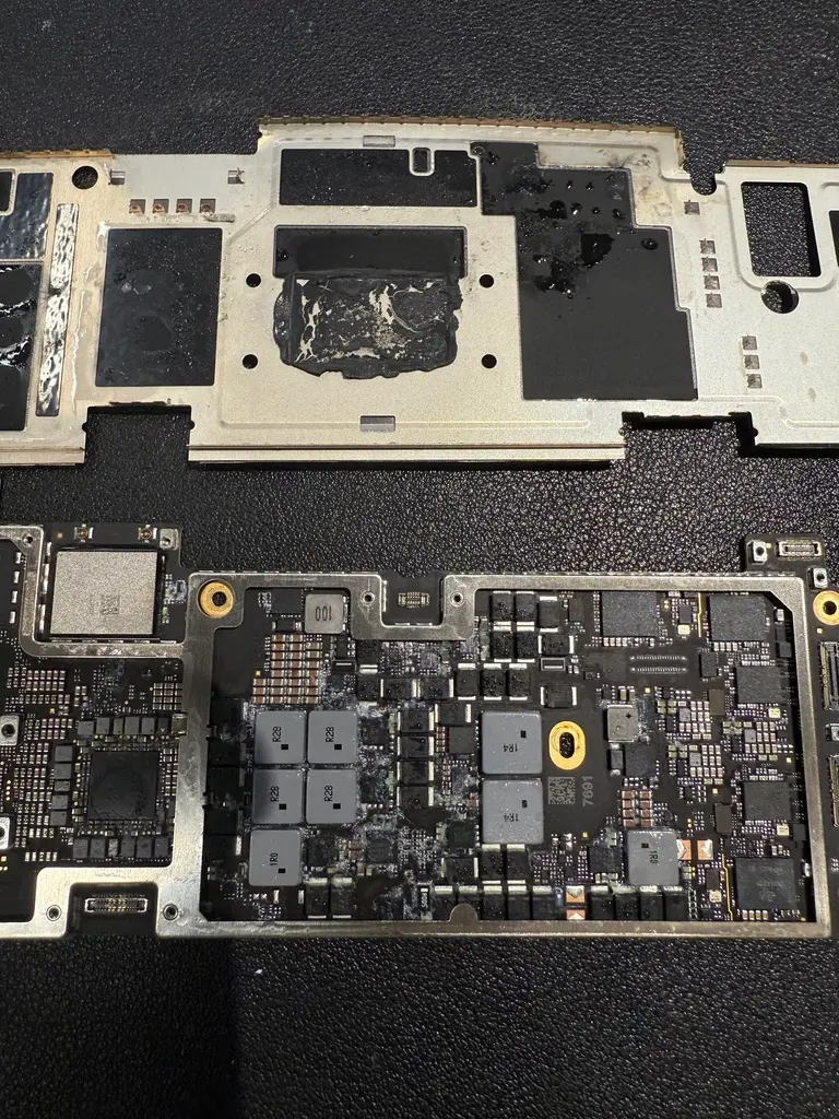MacBook 主機板拆除金屬屏蔽罩後的嚴重浸水腐蝕特寫,清晰可見精密電子元件周圍大面積的液體殘留與氧化短路痕跡
