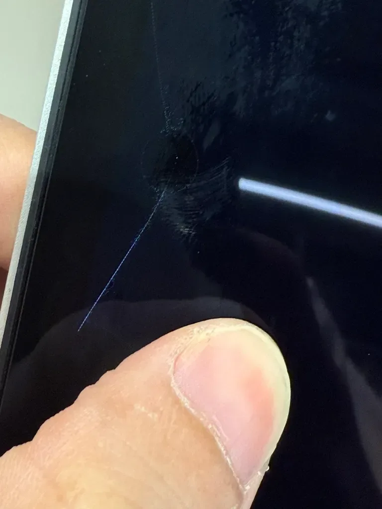 MacBook 螢幕玻璃細裂痕特寫,肉眼需近看才能發現