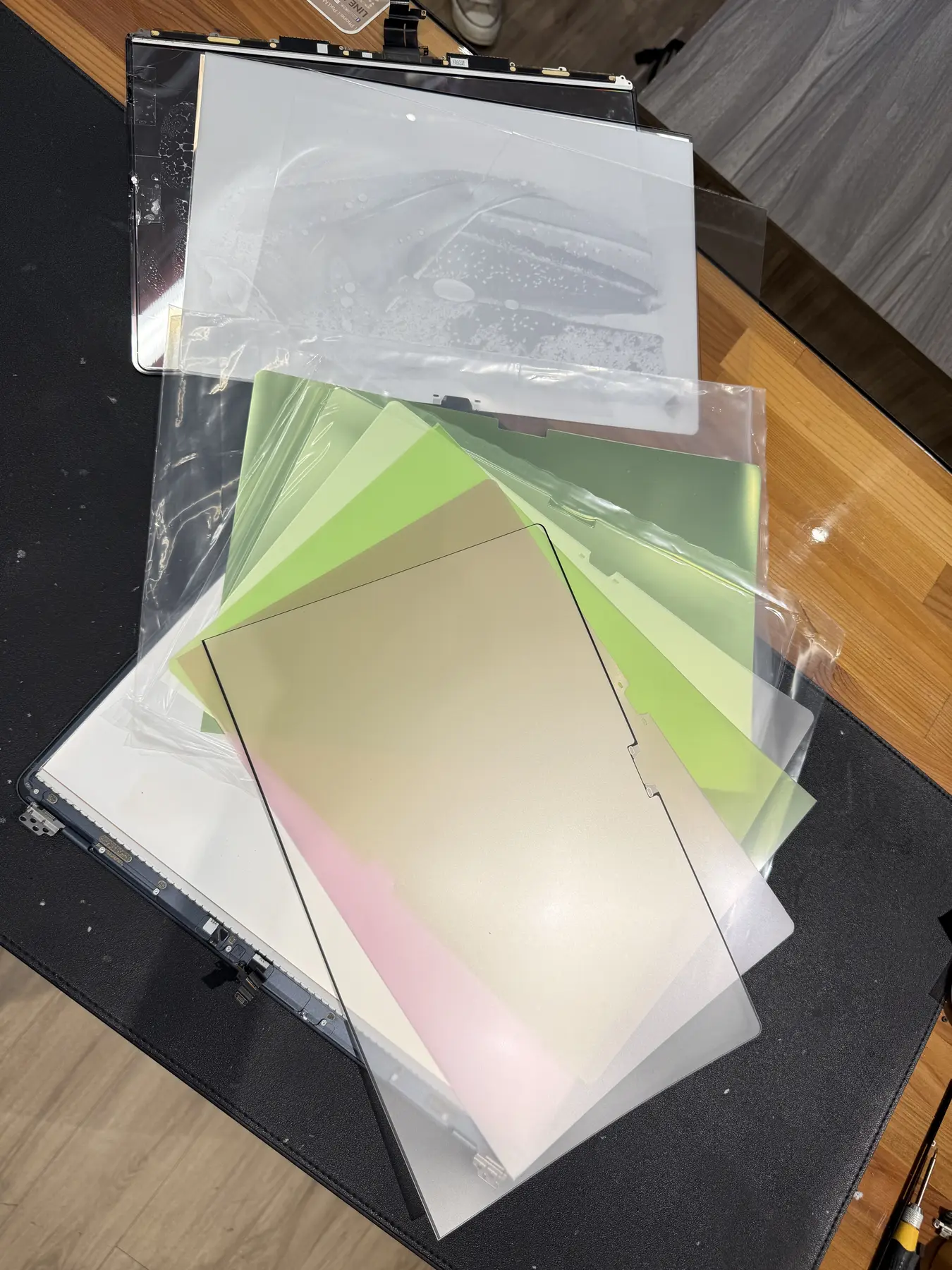  螢幕進水只要烘乾 迷思實測：拆解後排列出的六片背光光學膜層與液晶面板，顯示螢幕總成的多層結構